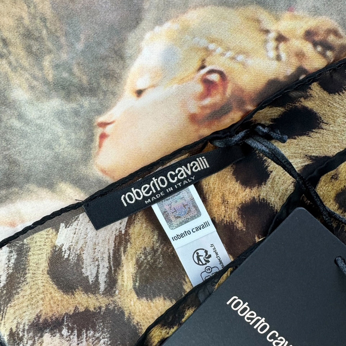 Leopard print bag with &#39;Roberto Cavalli&#39; branding and a close-up of a face on the fabric.